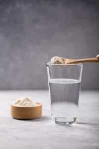 Wasserglas mit Kollagen Puder und Löffel